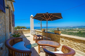 A terrace with outdoor furniture, a table, chairs, and an umbrella. - Candice Luxurious Historic Villa, Rentado Vacation Rental Management (Rethymno)