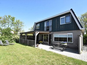 Ein zweigeschossiges Haus mit Balkon, überdachter Veranda und befestigter Auffahrt.