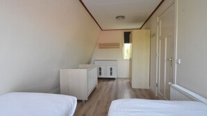 A room with two beds, a white cabinet, and a door leading to another room. - Holiday Home With Infrared Sauna in Callantsoog (Callantsoog)