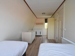 Ein Zimmer mit zwei Betten, einem weißen Schrank und einer Tür zu einem anderen Raum.