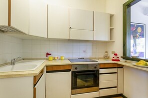 A kitchen with white cabinets, a sink, a stove, and a window with a view. - A comfortable apartment with a balcony that sleeps up to four people, located within the Campoverde Residence in Vernole—set in a Mediterranean pine forest between San Cataldo and the Le Cesine Nature Reserve. The property is just a short distance from (Campo Verde)