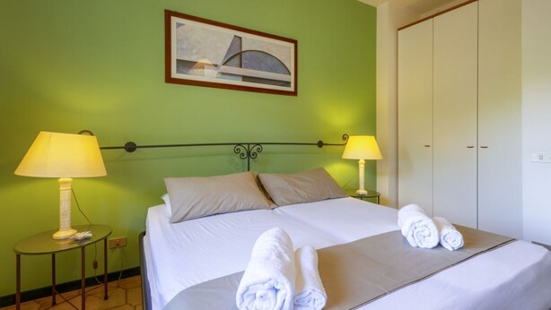 Une chambre d’hôtel avec un lit, deux lampes de chevet, un tableau au mur et une armoire.