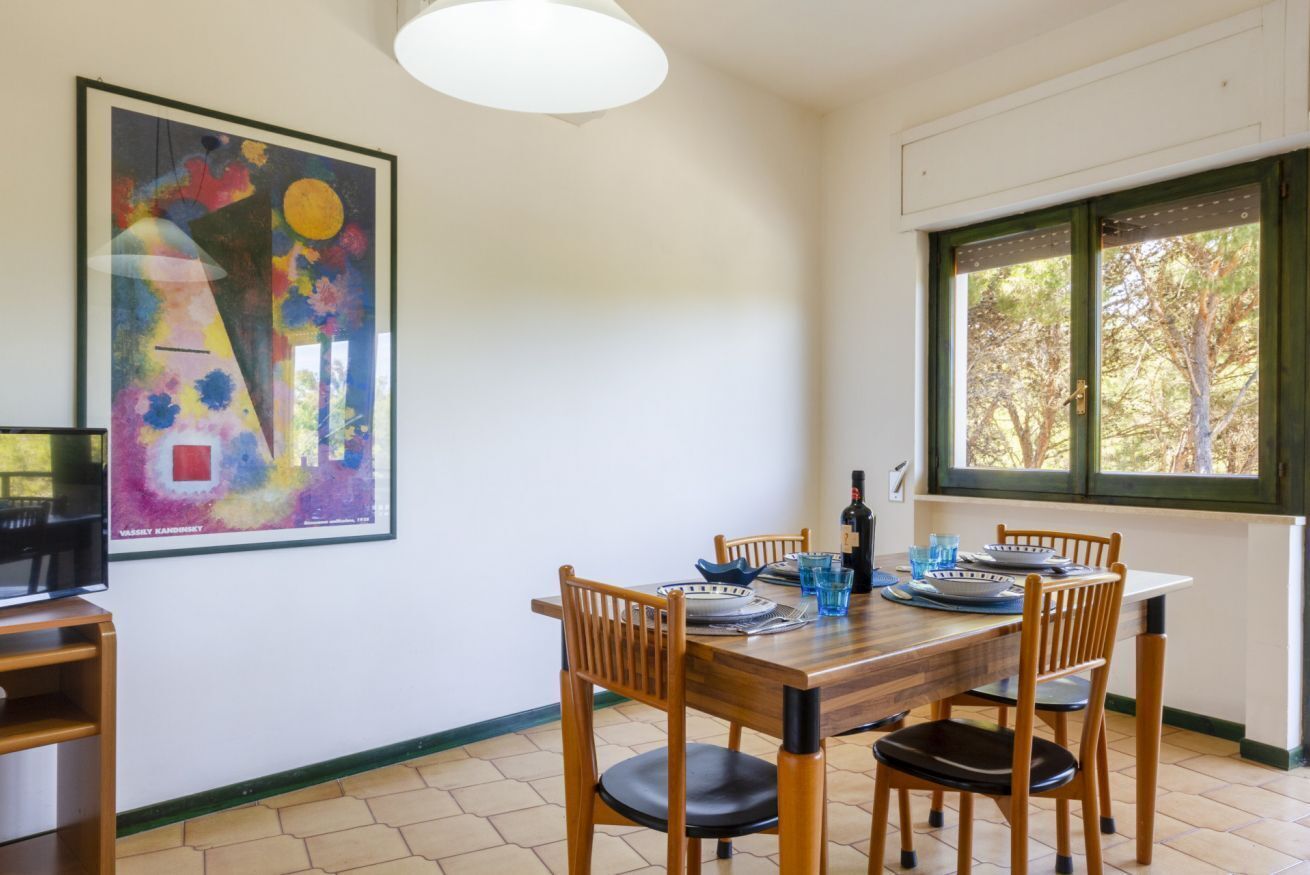 Un coin repas avec une table en bois, des chaises et un tableau accroché au mur.