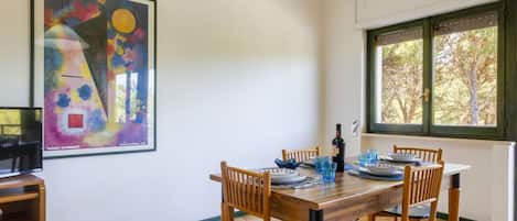 Un coin repas avec une table en bois, des chaises et un tableau accroché au mur.