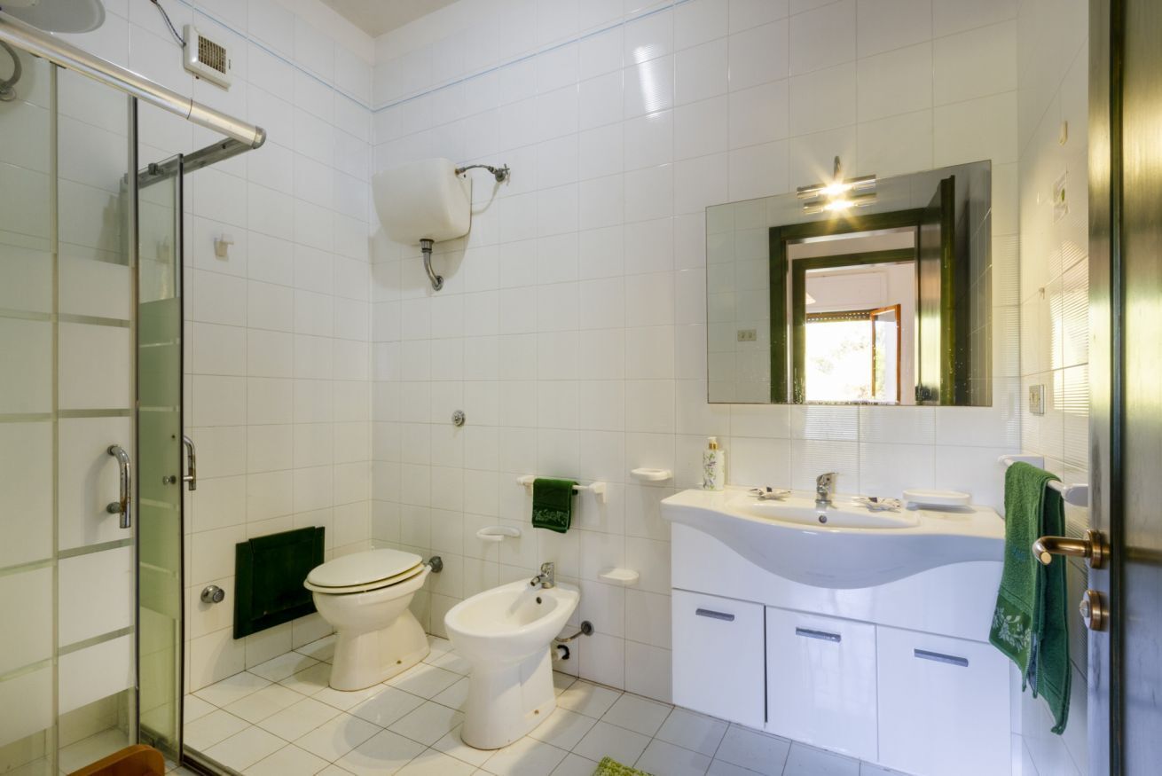 Ein Badezimmer mit Duschkabine, Toilette, Bidet, Waschbecken und Spiegel.