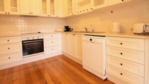 A kitchen with white cabinets, a dishwasher, an oven, and a coffee maker.