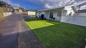 A residential property with a well-maintained lawn, a driveway, and a white picket fence.