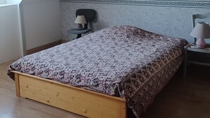 Une chambre avec un plafond en pente, un lit avec une literie à motifs, deux lampes de chevet et une petite table avec une lampe.