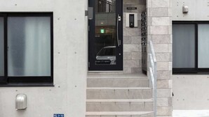 Un edifici modern amb una porta negra, una escala que condueix a l'entrada i una placa amb el número del portal.