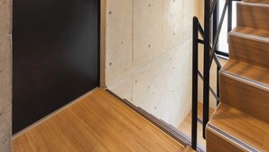 Una escala de fusta amb baranes negres que condueix a una porta negra amb un senyal de número.