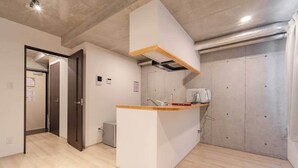 Cuina moderna amb taulell de fusta, una barra de rentar integrada i un mur de formigó.