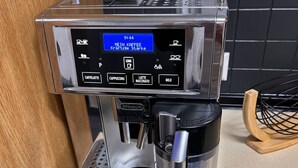 Eine Kaffeemaschine mit digitalem Display, Milchaufschäumer und Tropfschale.
