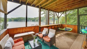 A covered outdoor seating area with wicker furniture, a glass table, and a view of a lake. - 2 Mi to Six Flags: Lakefront 2-Camp Combo (Queensbury)