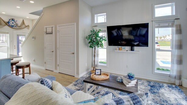 A living room with a sofa, a coffee table, a TV, and a plant. - Walk to Beach! North Padre Home w/ Pool Access (Corpus Christi)