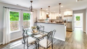 A modern kitchen with a dining area, large windows, and a view of greenery. - 2 Acres & Creek Access! Private Leicester Escape (Leicester)