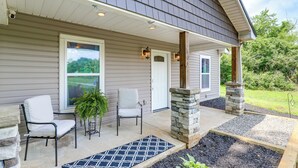 A house with a covered porch, two chairs, a potted plant, and a stone pillar. - 2 Acres & Creek Access! Private Leicester Escape (Leicester)