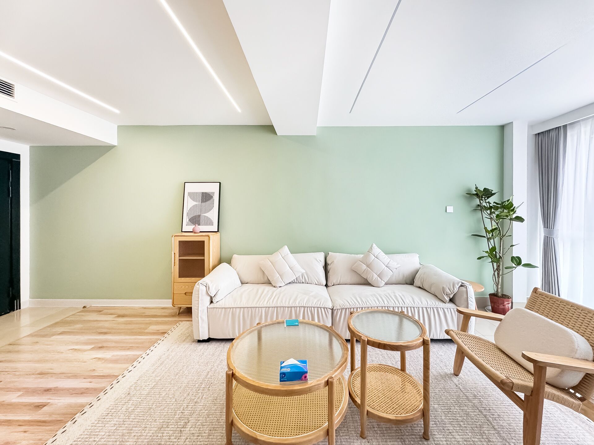 A modern living room with a sofa, two round tables, a side table, and a potted plant.