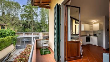 A balcony with a green metal chair, a small table, and a drying rack.