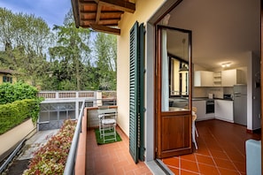 A balcony with a green metal chair, a small table, and a drying rack. - Giano Della Bella (Florence)