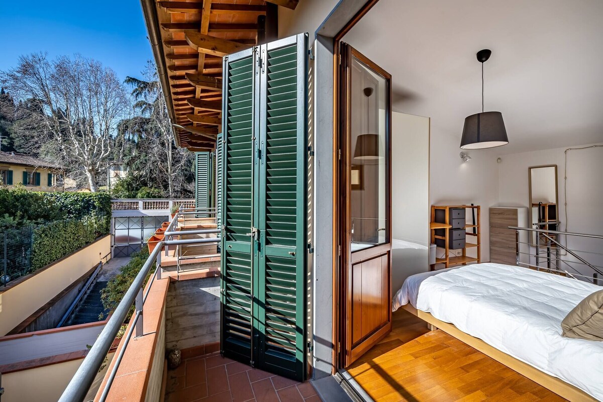 Een slaapkamer met een bed, een garderobe en een balkon met groene luiken.