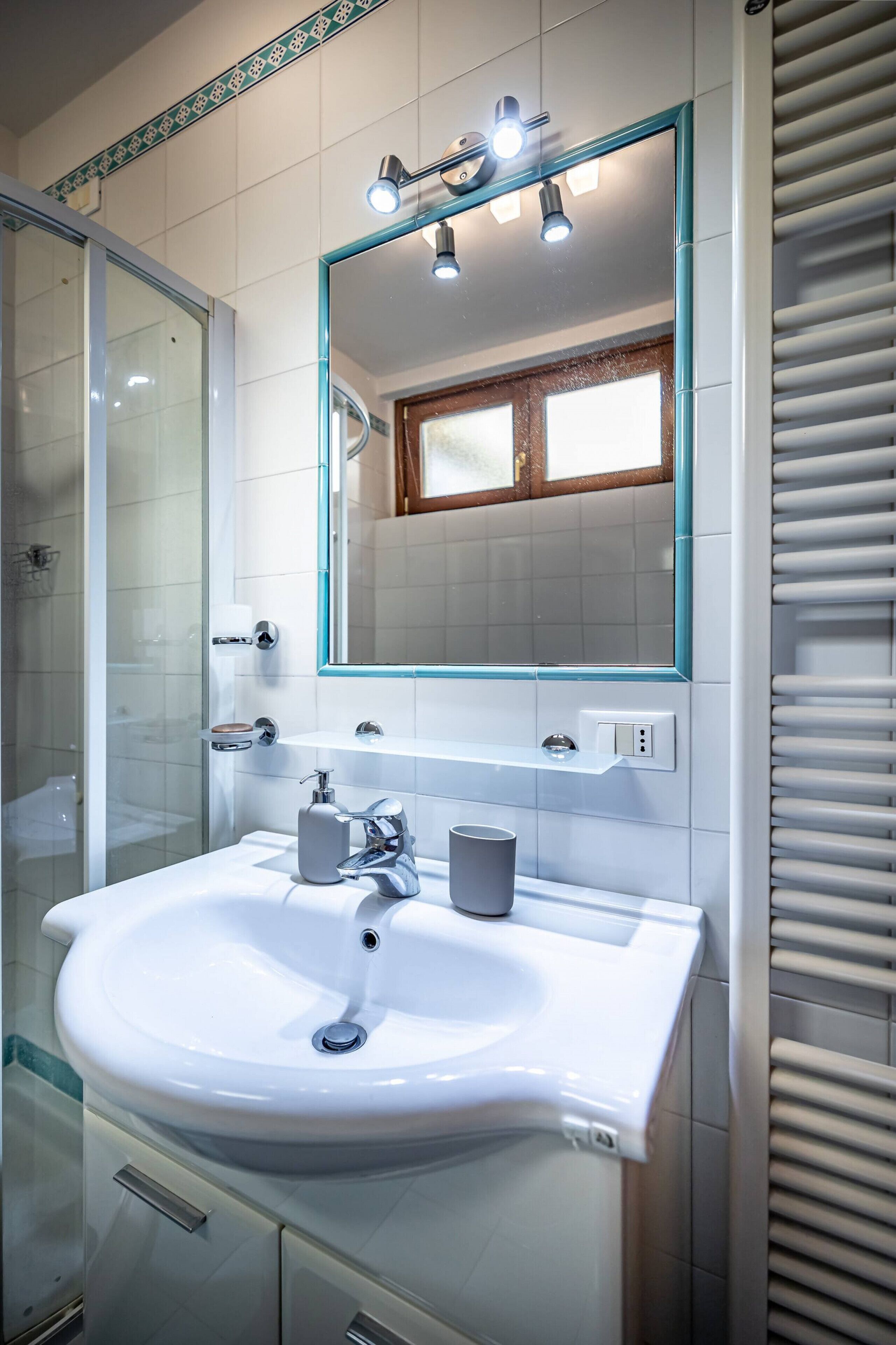 A bathroom with a white sink, a mirror, and a shower.