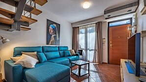 A modern living room with a blue sectional sofa, a small side table, and a wooden ceiling structure. - Giano Della Bella (Florence)