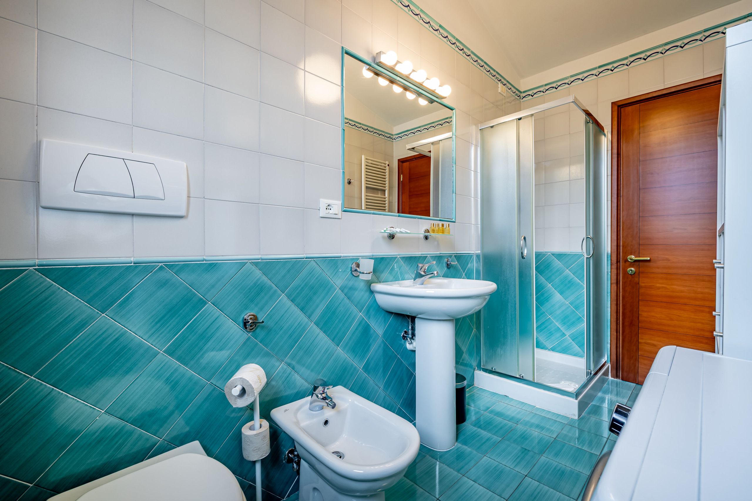 Un bagno con un lavandino bianco, un bidet, un water e una zona doccia.