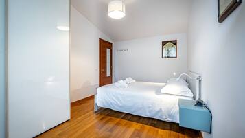Une chambre d’hôtel avec un lit, une table de chevet, une lampe, une carte accrochée au mur et un plancher en bois.