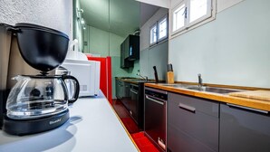 Uma cozinha moderna com cafeteira, máquina de lavar loiça e bancada de madeira.