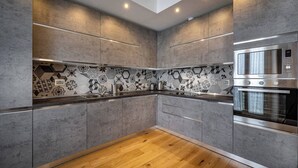 Eine moderne Küche mit grauen Schränken, einer gemusterten Spritzschutzwand und einer eingebauten Mikrowelle.