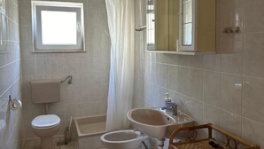 Un bagno con toilette, bidet, lavabo e uno specchio sopra il lavabo.