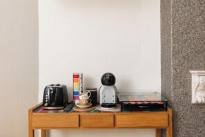 Ein kleiner Holztisch mit einer Kaffeemaschine, einem Toaster, einer Tasse und einer Teedose.