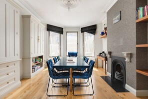 A dining room with a large table, chairs, a fireplace, and bookshelves. - New! Modern Family 4BR Home | Patio | Harringay (Greater London)