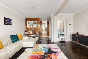 Ein modernes Wohnzimmer mit einer Couch, einem farbenfrohen Teppich, einer Holzvertäfelung und einem Bücherregal.