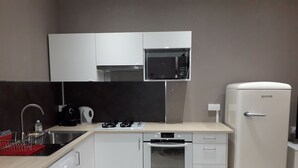A compact kitchen with a washing machine, a microwave, a stove, and a refrigerator. - A charming 32 m² studio apartment with an adjoining terrace. (Les Pennes-Mirabeau)