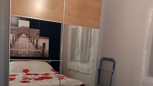 A bedroom with a bed, a wardrobe, a window with curtains, and a metal ladder. - A charming 32 m² studio apartment with an adjoining terrace. (Les Pennes-Mirabeau)