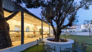 A modern building with a glass facade, outdoor seating area, and a tree planter. - Monte Taxco 9 Apartment (Torrent)