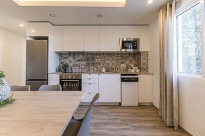 Een moderne keuken met witte kasten, een inbouwoven en een vaatwasser.