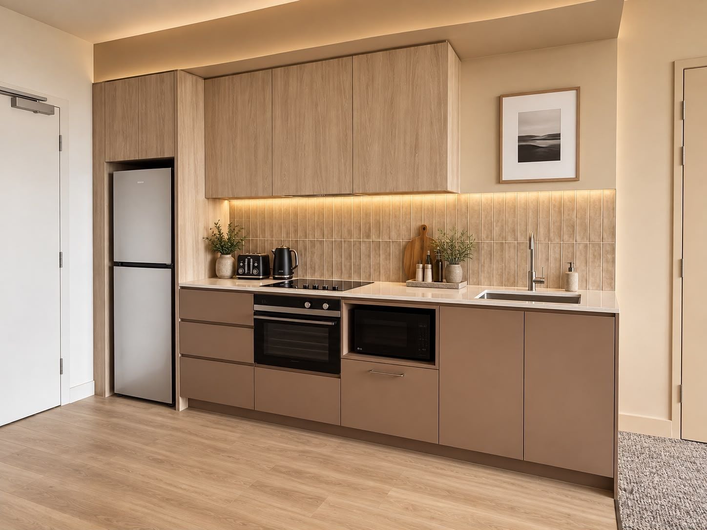 Eine moderne Küche mit Holzausbau, Backofen, Geschirrspüler und einer Arbeitsplatte mit Wasserkocher und Toaster.