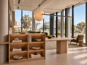 A modern interior with a wooden bookshelf, a round table, and a view of the outside.