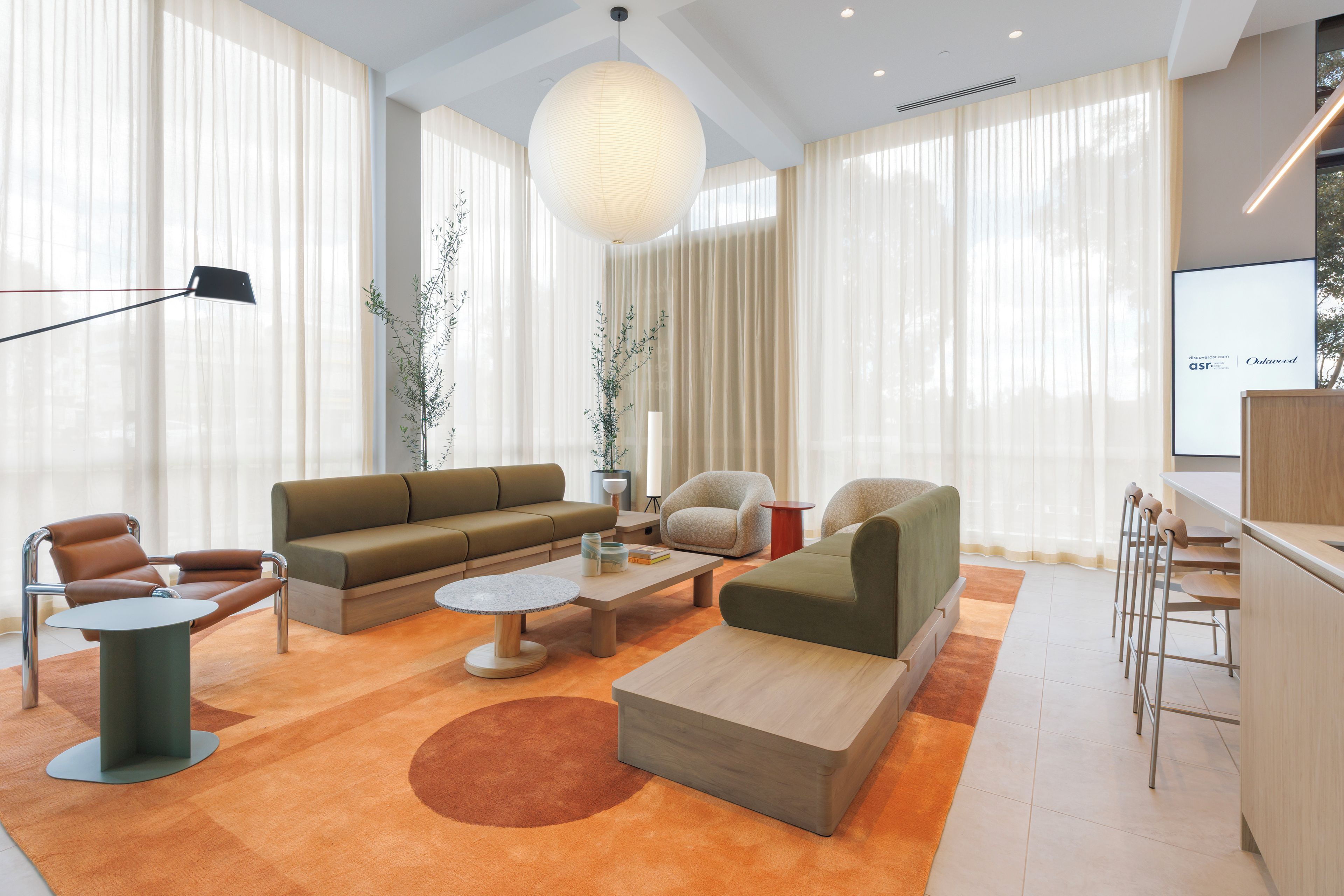 A modern living room with a sofa, armchairs, a coffee table, and a dining area with chairs.