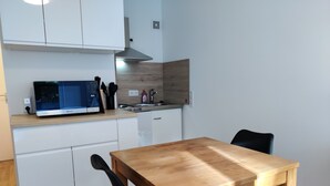 Une cuisine compacte équipée d’un four à micro-ondes, d’un évier et d’une table en bois.