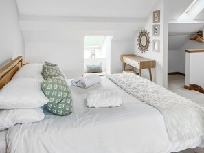 Un dormitorio ordenado con cama, almohadas, una alfombra mullida, un escritorio y un espejo.