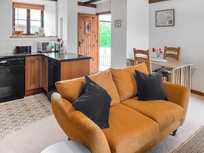 Ein gemütlicher Wohnbereich mit einer Couch, einem Esstisch und einer Küche mit Holzschränken und einem Geschirrspüler.
