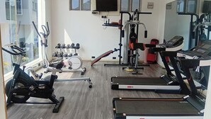 Een sportschool met loopbanden, een hometrainer en krachtapparaten.