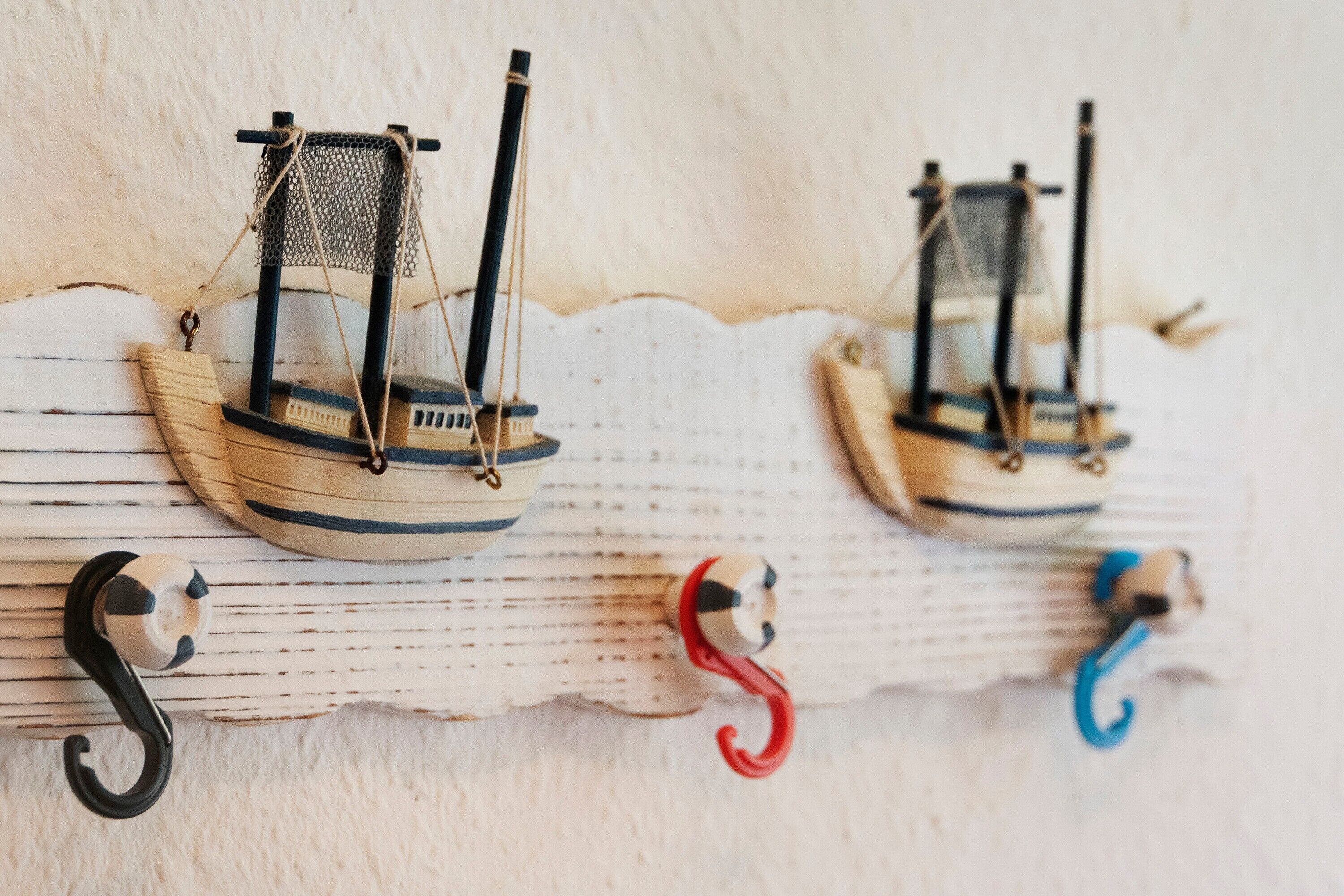 Two model sailboats mounted on a wooden surface with hooks below.