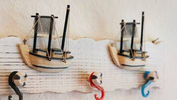Two model sailboats mounted on a wooden surface with hooks below.
