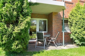 Eine Terrasse mit Tisch und Stühlen, einer Backsteinmauer und einem Fenster.