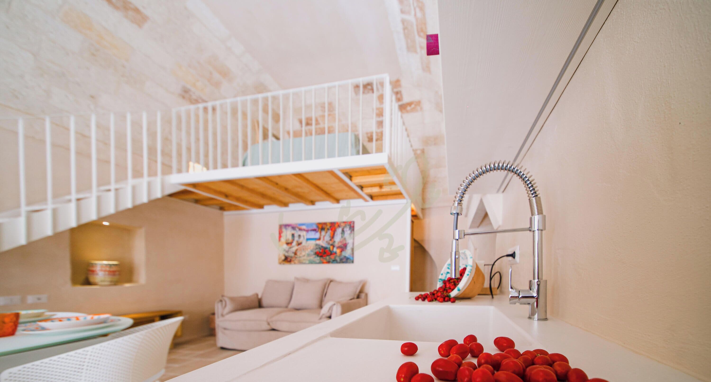 A modern interior with a bunk bed, a sink with red fruits, and a painting on the wall.