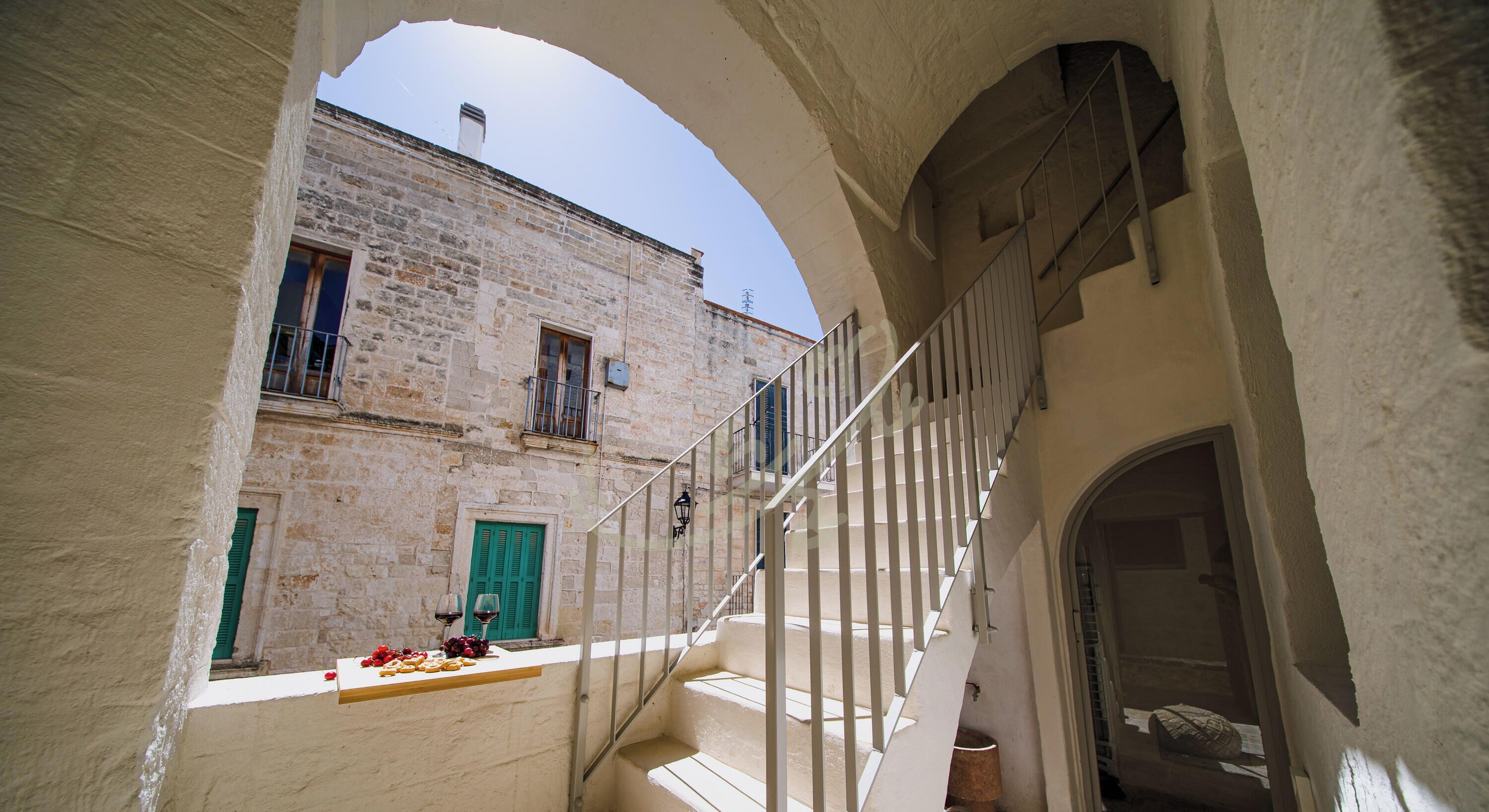Uma viela estreita com uma escadaria que leva a um edifício com uma porta verde e janelas.